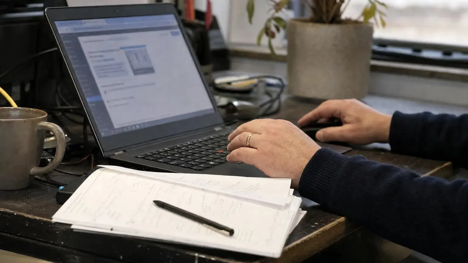 Handen naast een laptop met een generieke websitebeheeromgeving
